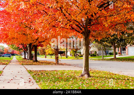 Zona suburbana di marciapiede e via in autunno guardando in discesa Foto Stock