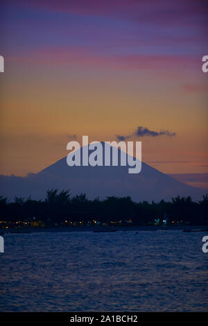 Gili Trawangan come si vede dal Gili Meno con il Monte Agung in background, Bali Indonesia dopo il tramonto. Foto Stock