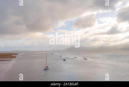 Il Menai Strait a Beaumaris. Le barche sono ormeggiate vicino alla terra con una barca in primo piano. Una pesante cloud è sopra. Foto Stock