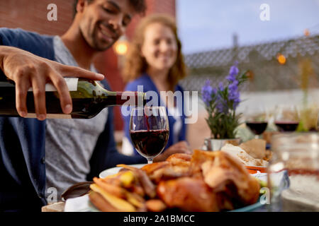 Varie coppia avente la cena e un bicchiere di vino al fresco in contesto urbano Foto Stock