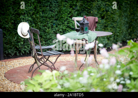 Tipico giardino inglese con un piccolo tavolo e sedie per esterno area con posti a sedere Foto Stock