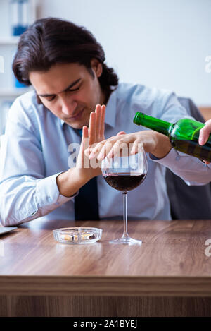 Il dipendente di sesso maschile di bere alcolici e fumare sigarette a workpla Foto Stock