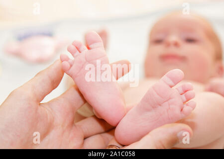 Padre detiene i neonati feets. Tiny gambe in mano d'uomo Foto Stock