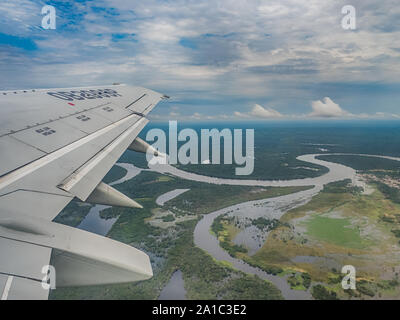 Vista dalla finestra di aereo. Ala di un aeroplano che vola sopra le nuvole oltre il fiume del Amazon. Vista superiore della foresta pluviale amazzonica. Il Perù, Brasile. La Colombia. Foto Stock