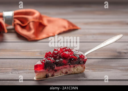 Pezzo di torta con frutti di bosco: lamponi, ribes, fragole sulla pala su sfondo di legno, in background Foto Stock