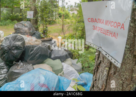 Regione di Leningrado, Russia - 6 Agosto 2019 - una discarica illegale in una foresta e 'no fly tipping" segno su una struttura ad albero Foto Stock