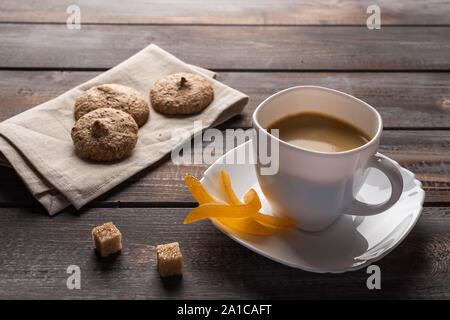 Tazza di caffè nero con arance candite e zollette di zucchero. I cookie sul tovagliolo di lino Foto Stock