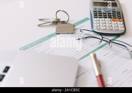 Domanda di credito ipotecario formano con le chiavi di casa, un paio di occhiali, una penna, un computer portatile e di una calcolatrice Foto Stock