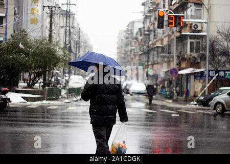 Un uomo con un sacchetto di plastica che attraversa la strada in Nanjing, Cina Foto Stock