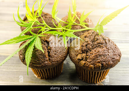 La Cannabis cioccolato cupcake muffin e foglie di canapa sul tavolo di legno Foto Stock