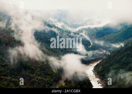 Mist, nebbia e nuvole temporalesche muoversi sopra i binari della ferrovia e le montagne in Feather River Canyon di Butte County, California. Foto Stock