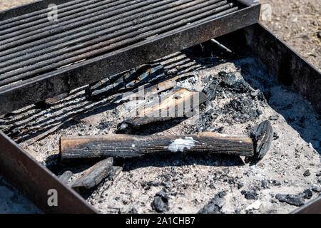 Primo piano di legno bruciato i registri in una buca per il fuoco grill durante il giorno in campeggio nel fiume verde campeggio in Dinosaur National Monument in Utah Foto Stock