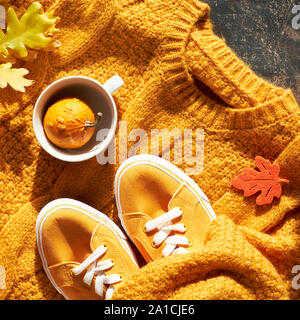 Autunno laici piatta con maglione giallo, zucca decorativa in tazza da tè e foglie di autunno, composizione quadrata Foto Stock