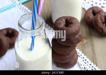 Una pila di ciambelle di cioccolato e un bicchiere di latte fresco Foto Stock