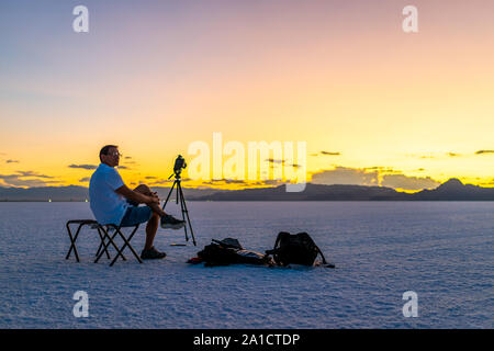 Bonneville Saline vicino a Salt Lake City, Utah al crepuscolo colorato dopo il tramonto con sale di viola e uomo seduto a guardare con vista orizzonte Foto Stock