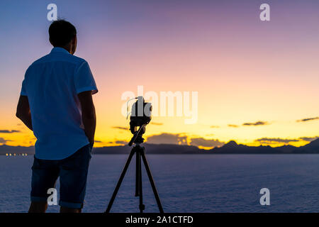 Bonneville Saline vicino a Salt Lake City, Utah al crepuscolo colorati con cielo viola e uomo in piedi dal treppiede con fotocamera facendo il time lapse fotografi Foto Stock