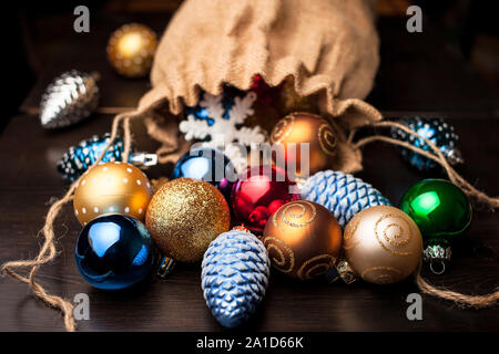 Le decorazioni di Natale si versato da un intero sacchetto di tela su una tavola di legno Foto Stock