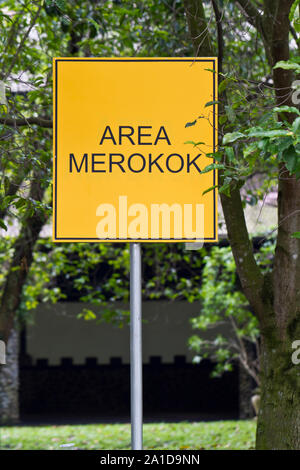 Area fumatori e digital signage in indonesiano mescolare con la lingua inglese Foto Stock