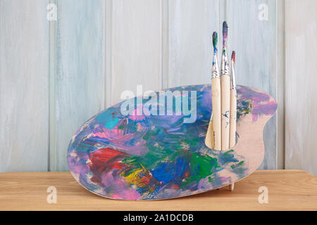 Arte in legno tavolozza con vernici e spazzole sul colore di sfondo in legno Foto Stock