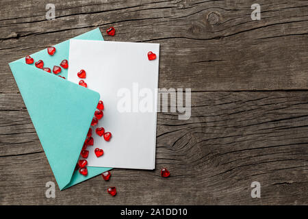 Lettera d'amore con cuori rossi. Modello vuoto con posto per il testo su una cartolina. Busta verde sul vecchio sfondo di legno. mock-up. Foto Stock