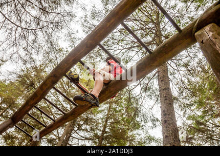 Felice ragazzo divertirsi salendo sulla scaletta nella foresta. Foto Stock