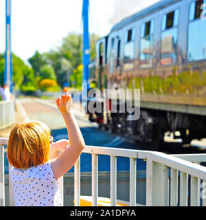 Giovane ragazza agitando per un Ribble Steam Railway treni passeggeri attraversando il ponte girevole sul Dock di Preston Foto Stock