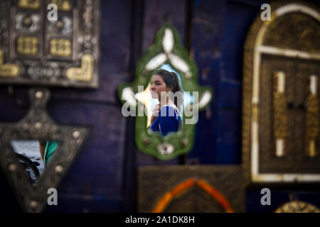 Una donna è riflessa in uno specchio al di fuori di un negozio a Essaouira, Marocco, Africa Foto Stock