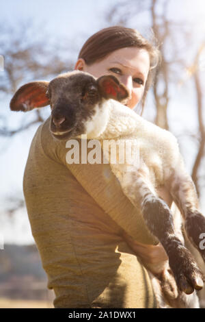 Giovane donna tenendo un agnello, il concetto di protezione degli animali e di amorevole Foto Stock