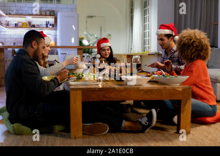 La millenaria amici adulti festeggiano il Natale insieme a casa Foto Stock