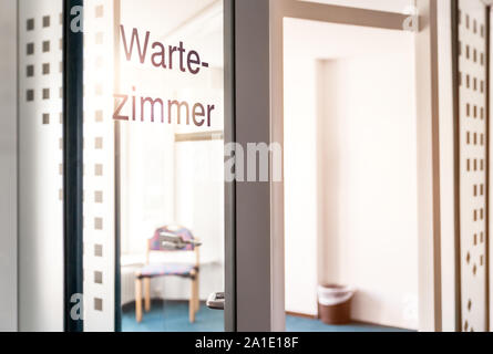 Stanza vuota con porta di vetro e la parola tedesca wartezimmer che significa sala di attesa Foto Stock