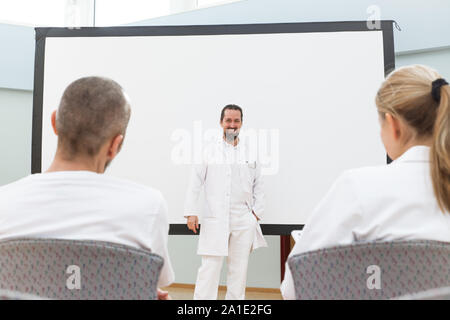 Medico è in piedi di fronte a una lavagna vuota dando una lezione o briefing Foto Stock