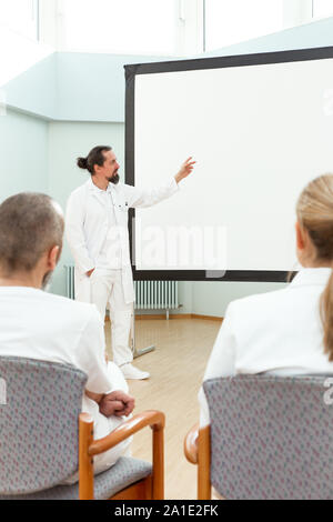 Medico è in piedi di fronte a una lavagna vuota dando una lezione o briefing Foto Stock