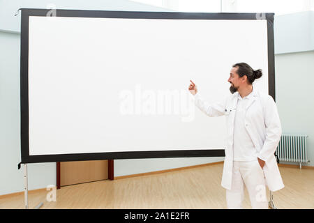 Medico è in piedi di fronte a una lavagna vuota dando una lezione o briefing Foto Stock