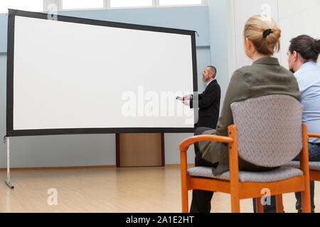 Uomo d affari con la compressa, forse un allenatore è in cerca di un Canvas vuoto Foto Stock