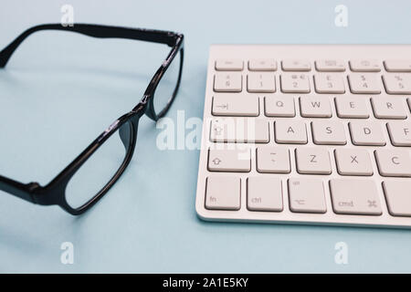 Tastiera per computer Occhiali minimal home office blu brillante colore di sfondo vista superiore Foto Stock