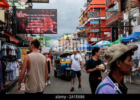 BANGKOK, Thailandia: i turisti a piedi lungo la Khao San Road di Bangkok, Thailandia Su agosto 22nd, 2019. Bangkok è vivace Khao San Road - una striscia famosa tra i turisti per il suo bilancio ostelli, cibo di strada e le bancarelle del mercato - è impostato per un £1,28 M faccia sollevare nel mese di ottobre di quest'anno. Per molti viaggiatori con lo zaino in spalla Khao San è il punto di partenza per i loro viaggi in tutto il sudest asiatico. Si tratta di un posto per incontrare altri viaggiatori e cenare fuori sul pad thai servita dalla strada di carrelli, sorseggiate dei cocktails da piccole vivacemente colorati delle benne o forse ottenere un mal consigliato tattoo. Un luogo entrambe le vistose e affascinante dove giovani turisti in Foto Stock