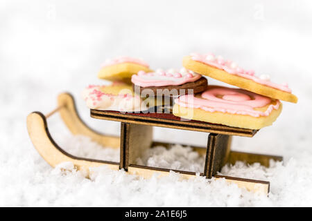 Rosa biscotti di Natale su una slitta di legno, sfondo bianco, concetto di forno e di stagione invernale Foto Stock