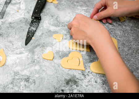 Donna sfinestratura a forma di cuore i cookies dal luminoso fresco pasta, processo di cottura Foto Stock