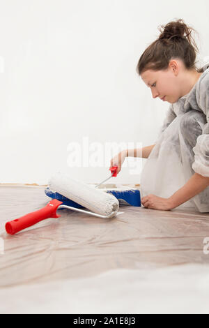 Giovane donna è la pittura del muro in bianco, miglioramento o cambiamento della casa Foto Stock