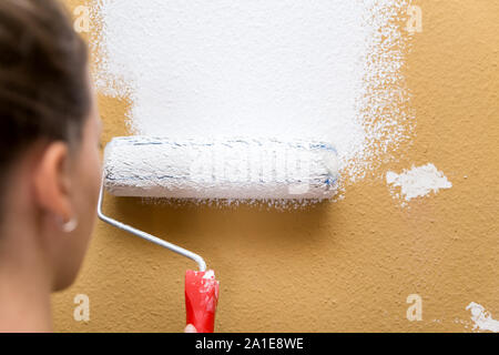 Giovane donna pittura un muro in bianco, cambiamento di casa, copyspace Foto Stock