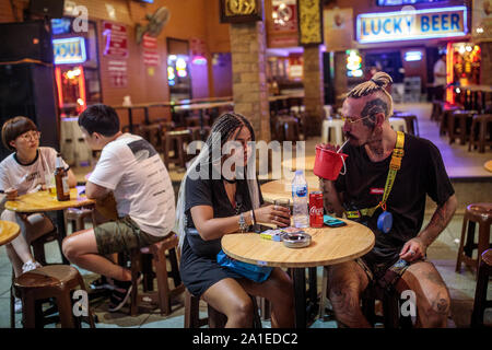 BANGKOK, Thailandia: Amici Sophia Abdi, 25 dall'Olanda e Jed Thomas, 30 dal Regno Unito hanno un drink al Lucky birra, dove entrambi hanno incontrato in Khao San Road di Bangkok, Thailandia Su agosto 23rd, 2019. Bangkok è vivace Khao San Road - una striscia famosa tra i turisti per il suo bilancio ostelli, cibo di strada e le bancarelle del mercato - è impostato per un £1,28 M faccia sollevare nel mese di ottobre di quest'anno. Per molti viaggiatori con lo zaino in spalla Khao San è il punto di partenza per i loro viaggi in tutto il sudest asiatico. Si tratta di un posto per incontrare altri viaggiatori e cenare fuori sul pad thai servita dalla strada di carrelli, sorseggiate dei cocktails da piccole vivacemente colorati benna Foto Stock