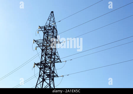 Traliccio metallico di una linea elettrica ad alta tensione con isolatori in vetro e un sacco di fili su uno sfondo di cielo azzurro Foto Stock