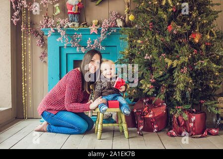 Ritratto di madre felice e adorabile baby festeggiano il Natale. Capodanno. Bambino con mom in addobbate a festa con camera t di Natale Foto Stock