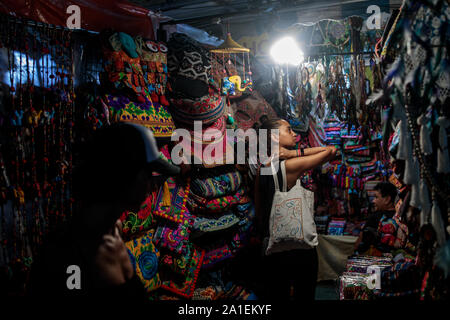 BANGKOK, Thailandia: turisti guardare attraverso i pezzi per la vendita in una fase di stallo a Khao San Road di Bangkok, Thailandia Su agosto 23rd, 2019. Bangkok è vivace Khao San Road - una striscia famosa tra i turisti per il suo bilancio ostelli, cibo di strada e le bancarelle del mercato - è impostato per un £1,28 M faccia sollevare nel mese di ottobre di quest'anno. Per molti viaggiatori con lo zaino in spalla Khao San è il punto di partenza per i loro viaggi in tutto il sudest asiatico. Si tratta di un posto per incontrare altri viaggiatori e cenare fuori sul pad thai servita dalla strada di carrelli, sorseggiate dei cocktails da piccole vivacemente colorati delle benne o forse ottenere un mal consigliato tattoo. Un luogo entrambe le vistose e c Foto Stock