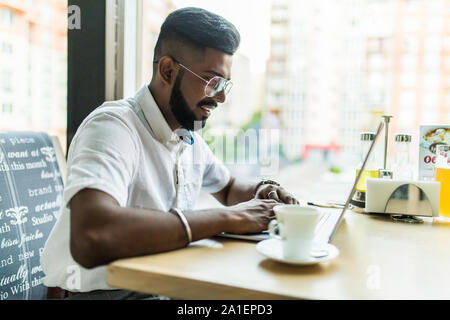 Esperto bello studente maschio della propria programmazione scuola facendo online la pratica di esercizio nella codifica di digitazione su computer portatili Tastiera in seduta cafe Foto Stock
