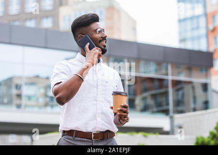 Uomo che parla al telefono cellulare e di bere il caffè Foto Stock