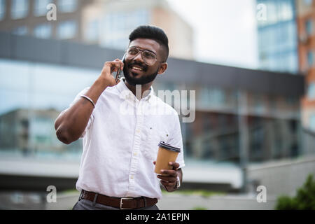 Uomo che parla al telefono cellulare e di bere il caffè Foto Stock