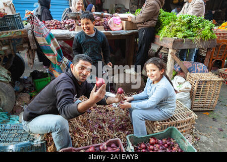 Alessandria, Egitto - 18 dicembre 2018: gli agricoltori egiziani famiglia pela le cipolle in vendita Foto Stock