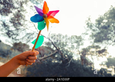 Mano trattiene un giocattolo girandola, concetto di ispirazione e di sogni in libertà. Foto Stock