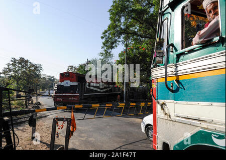 INDIA, Madhya Pradesh, Nimad regione, Khargone, attraversamento ferroviario con barriere chiuse, treno in marcia, locomotiva diesel Foto Stock